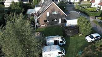 Eine Luftaufnahme eines Hauses mit Solarpanelen, umgeben von Bäumen und einem gepflegten Garten mit Spielgeräten.