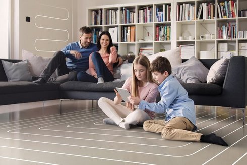 Eine Familie die in einem Wohnzimmer ist, in dem die Kinder auf dem Boden sitzen