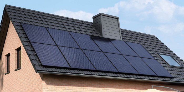 Die Dachfläche eines Hauses ist mit großen, schwarzen Solarpanelen ausgestattet, die umweltfreundliche Energie erzeugen.
