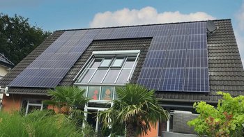 Ein modernes Haus mit einem schrägen Dach, das mit mehreren Solarpanelen bedeckt ist, umweltfreundliche Energie erzeugend.